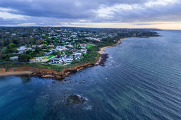 Fototapeta premium Aerial view of luxury houses on Mornington Peninsula coastline at sunset