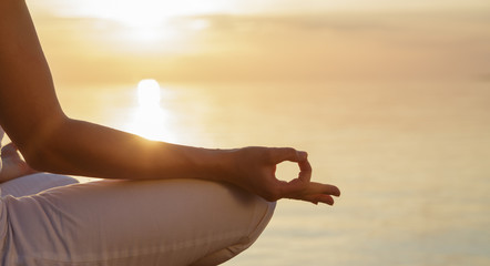 The concept of meditation. Part of the body of a woman in the lotus position, finger mudra against...