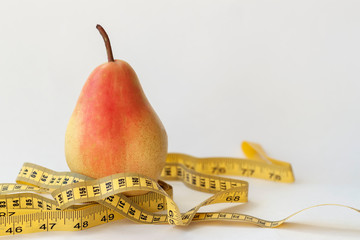 Ripe yellow pear and tape measure on light background, concept of a healthy lifestyle, diet