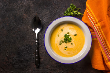 Seasonal autumn food - Spicy pumpkin soup with cream and pumpkin seeds.