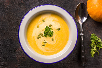 Seasonal autumn food - Spicy pumpkin soup with cream and pumpkin seeds.