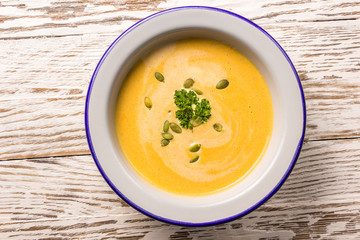 Seasonal autumn food - Spicy pumpkin soup with cream and pumpkin seeds.