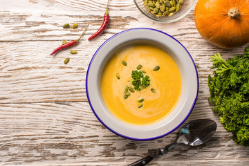 Seasonal autumn food - Spicy pumpkin soup with cream and pumpkin seeds.