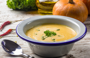 Seasonal autumn food - Spicy pumpkin soup with cream and pumpkin seeds.