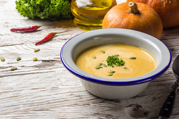 Seasonal autumn food - Spicy pumpkin soup with cream and pumpkin seeds.