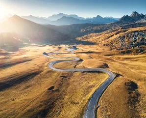 Photo sur Plexiglas Dolomites Winding road in mountain valley at sunset in autumn. Aerial view of asphalt road in Passo Giau. Dolomites, Italy. Top view of roadway, mountains, meadows with orange grass, blue sky and gold sunlight