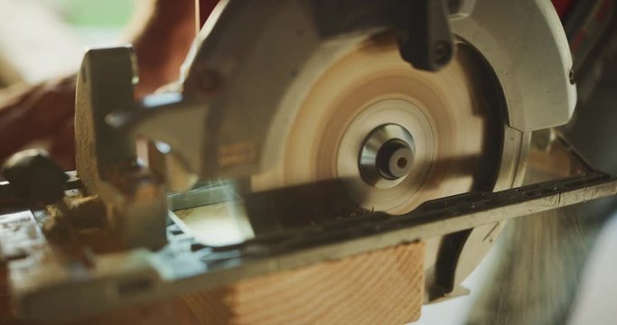 Close up shot of carpenter using skill saw to cut through wood