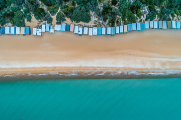 Bathing boxes, sandy beach, and turquoise ocean water - aerial top view