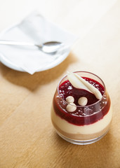 cheesecake with raspberries and decorated with white chocolade in glass on old wooden background top view