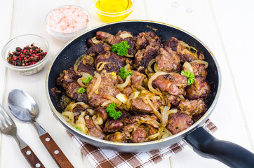 Frying pan with fried chicken giblets. Studio Photo