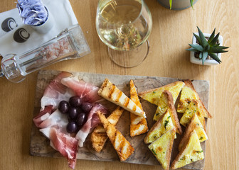 Appetizers table with italian antipasti snacks and wine in glass. Brushetta or authentic traditional spanish tapas set, cheese variety board over wooden  background. Top view, flat lay
