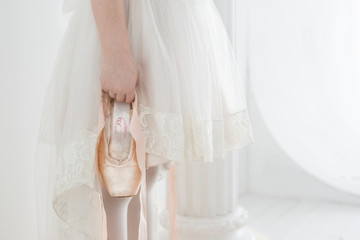 little girl ballerina in a beautiful white dress holding pointe shoes © ritiniya