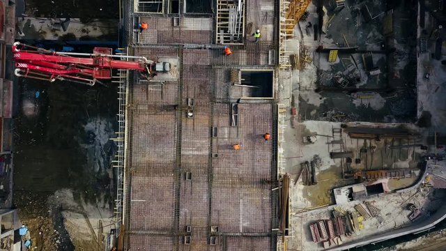 Aerial view of construction workers work on top of the building at construction site - Drone is rising up