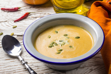 Seasonal autumn food - Spicy pumpkin soup with cream and pumpkin seeds.