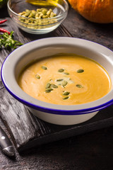 Seasonal autumn food - Spicy pumpkin soup with cream and pumpkin seeds.