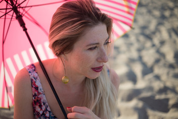 Blonde female makeup using pink umbrella sunscreen