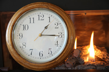 old clock on the background of a burning fire in the fireplace. Concept of time.