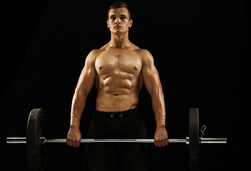 Fototapeta na wymiar Muscular young man holding barbell. Concept of training in the gym and functional training
