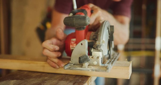 Skilled carpenter uses skill saw to cut wood