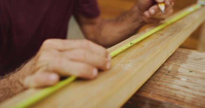 Skilled carpenter carefully measures and marks lengths on wood