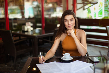 business woman in a cafe fills the documents. Reflections. Work outside the office.