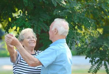 Cute elderly couple dancing outdoors. Time together