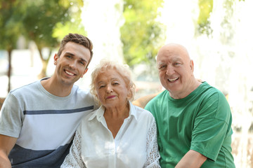 Man with elderly parents outdoors on sunny day