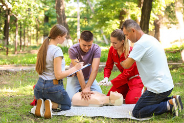 Group of people having first aid class with mannequin outdoors