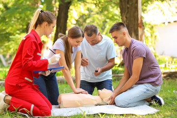 Group of people having first aid class with mannequin outdoors