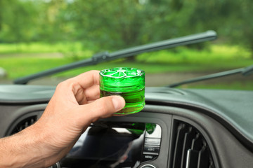 Man putting air freshener on dashboard in car, closeup