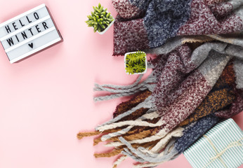 Christmas concept flat lay. Warm, cozy winter clothing, light box  and Christmas decorations frame on white background
