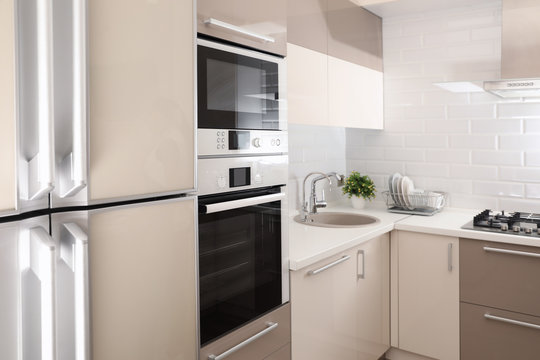 Modern kitchen interior with combination oven, microwave and fridge