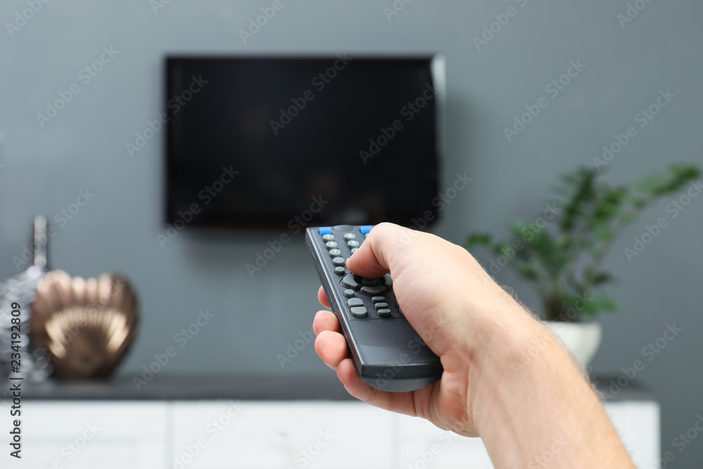 Poster man switching channels on plasma tv with remote control at home
