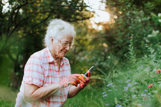 Senior woman using her phone while gardening