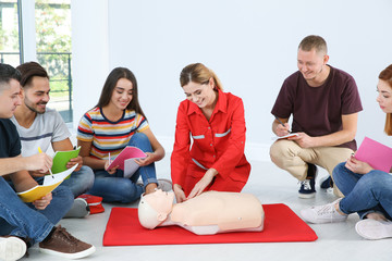 Instructor demonstrating CPR on mannequin at first aid class indoors