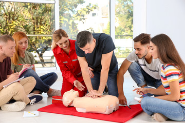 Group of people with instructor practicing CPR on mannequin at first aid class indoors - obrazy, fototapety, plakaty