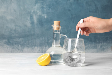Woman mixing vinegar and baking soda in glass on table. Space for text