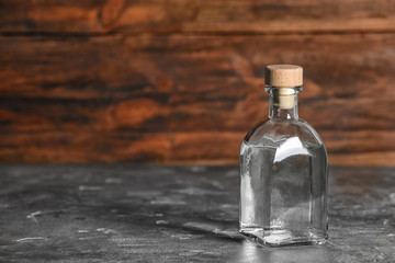 Fototapeta na wymiar Glass bottle with vinegar on wooden background. Space for text