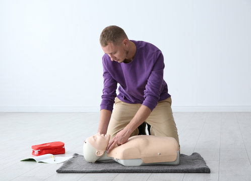 Man practicing first aid on mannequin indoors