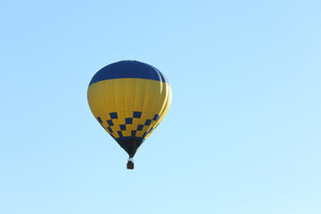 Fototapeta premium Colorful hot air balloon flying in blue sky. Space for text