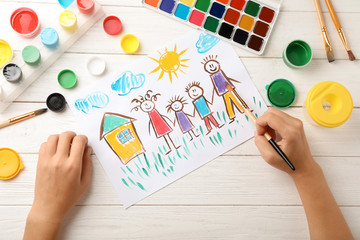 Girl painting picture of family on table, top view