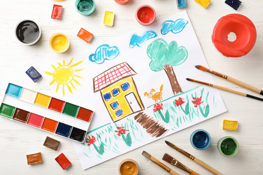 Flat lay composition with child's painting of house on table