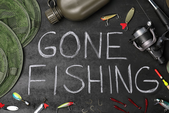 Flat lay composition with angling equipment and words "GONE FISHING" on dark background