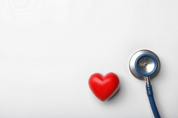 Stethoscope for checking pulse and red heart on white background, top view. Space for text