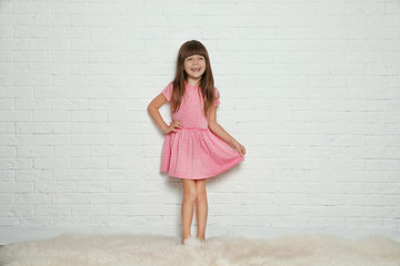Portrait of cute little girl against brick wall
