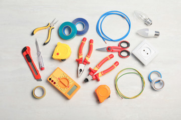 Flat lay composition with electrician's tools on light background