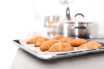 Oven sheet with freshly baked croissants on kitchen counter