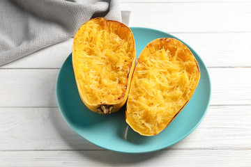 Plate with cooked spaghetti squash on white wooden background