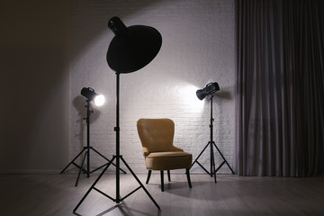 Interior of modern photo studio with professional lighting equipment and armchair