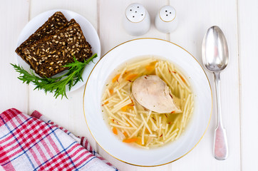 Chicken broth noodle soup on white wooden background